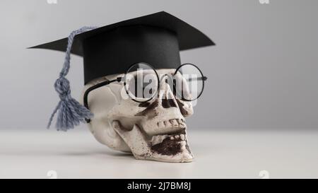 Crâne en plastique avec bonnet et lunettes universitaires. Banque D'Images