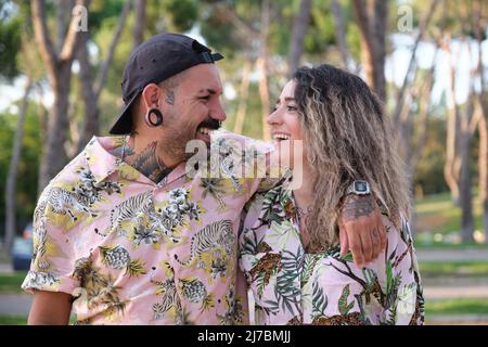 Jeune couple cool tatoué regardant l'un l'autre et rire. Banque D'Images