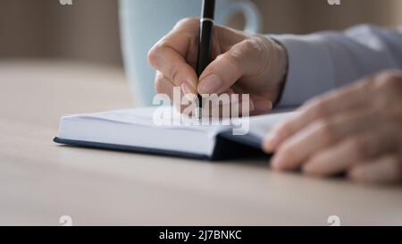 Les mains d'une femme d'affaires rédigeant des notes dans un ordinateur portable en gros plan Banque D'Images