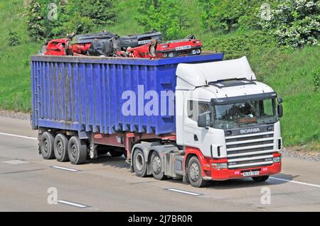 Camion hgv SCANIA blanc non marqué et remorque basculante articulée bleue chargée de bennes de ferraille écrasées sur la route autoroutière britannique Banque D'Images