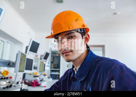 Ust'-Kamenogorsk, Kazakhstan - 31 mai 2012 : usine de métallurgie du titane. Un jeune opérateur travaillant dans un casque orange contrôle le processus dans la salle de contrôle. Comp Banque D'Images