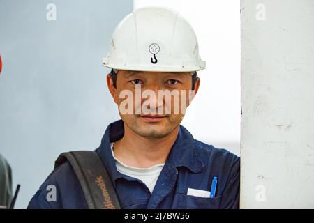 Ust'-Kamenogorsk, Kazakhstan - 31 mai 2012 : portrait d'un jeune ingénieur asiatique en casque blanc. Regarde directement dans l'appareil photo. Banque D'Images