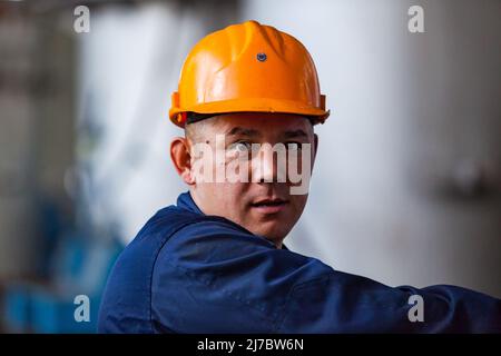 Ust'-Kamenogorsk, Kazakhstan - 31 mai 2012 : portrait d'un ouvrier asiatique en casque orange. Regarde directement dans l'appareil photo. Banque D'Images