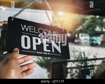 Panneau d'affichage ouvert avec texte blanc sur panneau en bois vintage noir « Bienvenue, nous sommes ouverts, entrez » suspendu sur la porte vitrée du café, café, magasin Banque D'Images