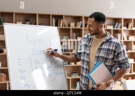 Joyeux enseignant arabe masculin enseignant la langue anglaise, expliquant le nouveau thème aux étudiants Banque D'Images