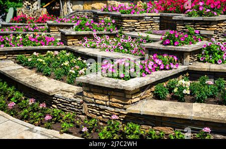 Aménagement paysager avec murs de soutènement et parterres de fleurs dans l'arrière-cour de la maison résidentielle. Aménagement paysager du jardin haut de gamme de la maison en été. Fleurs et plantes o Banque D'Images