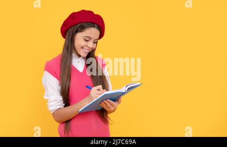 bonne fille d'école d'adolescence en béret français faire des notes dans le bloc-notes de planificateur ou bloc-notes, la connaissance Banque D'Images