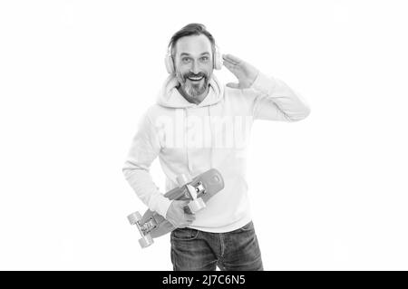 un homme souriant et expérimenté écoute de la musique isolée sur blanc. un homme en pull à capuche jaune avec planche à roulettes. Banque D'Images