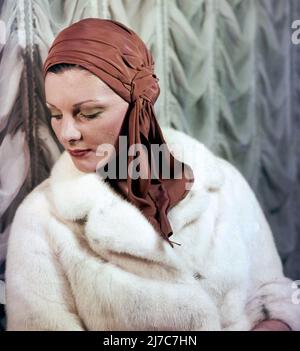Femme habillée en 20s- 40s automne-hiver mode, avec un manteau de fourrure et un enveloppement de tête de fantaisie Banque D'Images