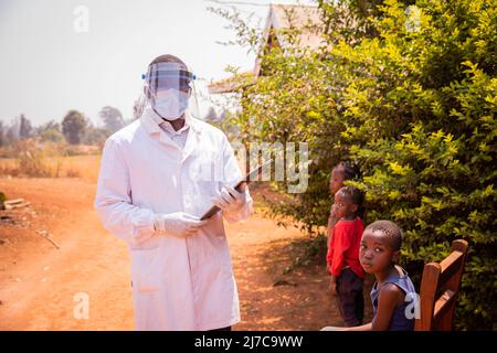 Le pédiatre africain rend visite à des enfants patients prêts à être examinés, portant un masque, un masque facial et des lunettes de protection pour se protéger pendant une pandémie Banque D'Images