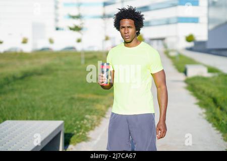 Sportif afro-américain fatigué avec de l'eau dans la ville Banque D'Images