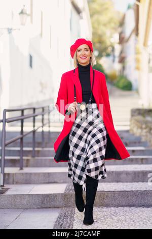 Une femme souriante et tendance qui marche dans la rue avec un appareil photo Banque D'Images