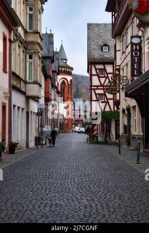 Homme marchant son chien dans une rue pavée de Bacharach, Allemagne pendant le confinement. Banque D'Images