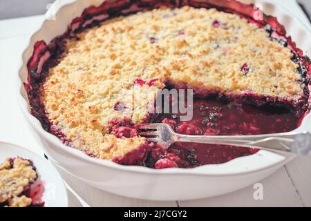 plat de cuisson en céramique blanche avec tarte aux myrtilles. fourchette laissée sur une tarte. cuisson à la maison, avec baies de jardin, repas sain. lumière directe du soleil Banque D'Images