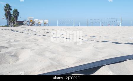 Joueurs jouant au volley-ball sur la plage, jeu de volley-ball avec balle et filet, côte de Californie, États-Unis.Des personnes actives défocacées sur le terrain de sport, sur la rive sablonneuse de l'océan.Arrière-plan cinemagraph en boucle sans couture. Banque D'Images