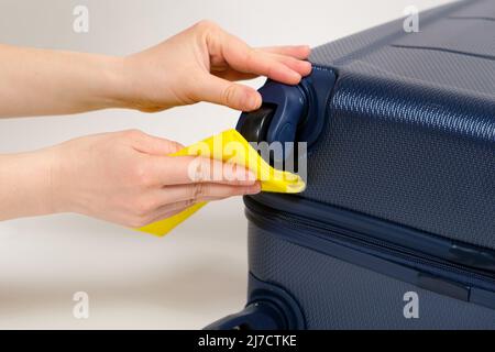 Une Femme Essuie Une Valise Bleue En Plastique De Voyage Avec Un Chiffon  Jaune