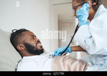 Fille dans une robe médicale écoute à souffle de père avec stéthoscope Banque D'Images