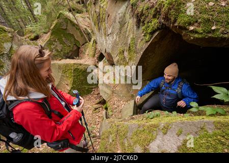 Femme randonneur regardant l'homme quitter la grotte dans le rocher Banque D'Images