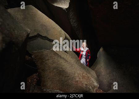 Femme regardant la lumière qui traverse le trou dans une grotte vide Banque D'Images