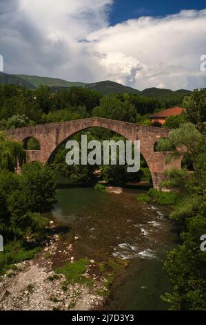 Ciel orageux au-dessus de l'arc gracieux du Pont Vell ou Vieux Pont au-dessus de la rivière ter à Sant Joan de les Abadesses, Ripollès, Catalogne, Espagne. Le pont du XIIe siècle a été reconstruit plusieurs fois, grâce à un tremblement de terre de 1428 et aux destructions causées par la retraite des troupes républicaines pendant la guerre civile espagnole. Banque D'Images