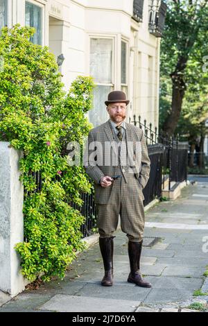 Bien habillé Anglais gentleman avec chapeau de melon debout dans la rue tenant un tuyau . Banque D'Images