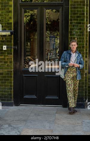 Homme élégant portant un pantalon camouflage sur le côté du pub Banque D'Images