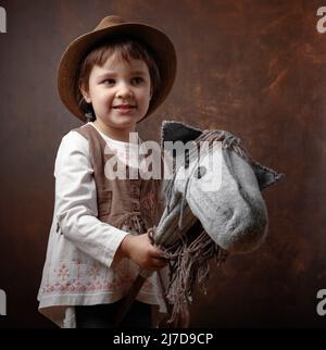 Une fille dans un chapeau et des vêtements nationaux ukrainiens joue avec un cheval fait maison. Banque D'Images