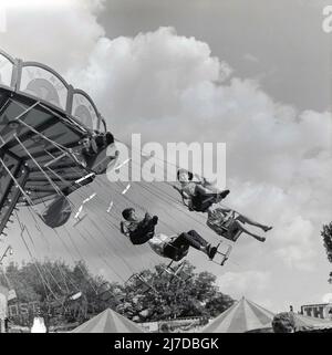 1969, historique, enfants et adultes sur un tour de foire tournante, connu sous le nom de balancement ou de balancement de chaise, Angleterre, Royaume-Uni. Dans certaines parties du monde, ils sont également connus sous le nom de « promenades en chaise ou en avion ». Banque D'Images