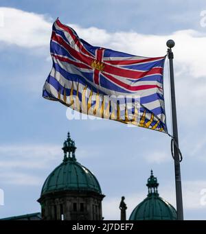 Drapeau de la province de la Colombie-Britannique, le Canada vole près des dômes des édifices du Parlement à Victoria. Banque D'Images