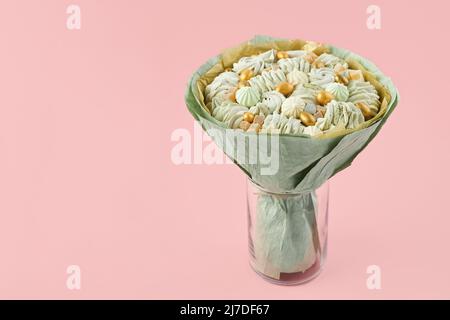 Bouquet unique de guimauves faites à la main enveloppées de papier vert debout dans un vase sur fond rose, espace de copie Banque D'Images