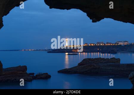 La vue de nuit du phare de Biarritz vue par l'arche de roche. France. Banque D'Images