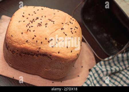 Pain frais maison parsemé de graines de lin et de sésame, cuit dans une machine à pain. Délicieuses pâtisseries maison. Banque D'Images