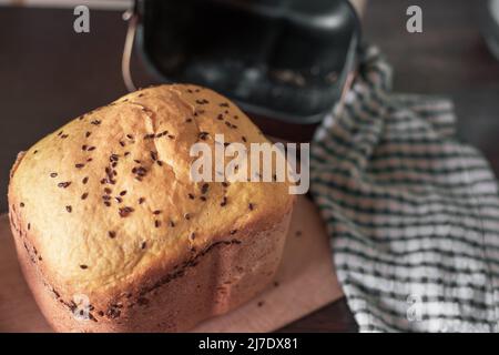 Pain frais maison parsemé de graines de lin et de sésame, cuit dans une machine à pain. Délicieuses pâtisseries maison. Banque D'Images