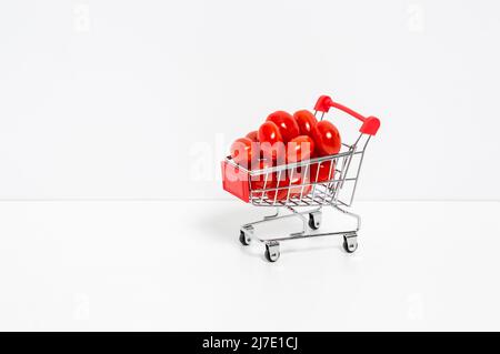 Tomates cerises ou roma dans un panier rouge isolé sur fond blanc. Acheter des légumes et des baies, une alimentation saine et des vitamines naturelles Banque D'Images