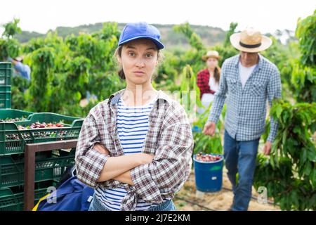 Jardinière féminine aux mains croisées posant dans le jardin Banque D'Images