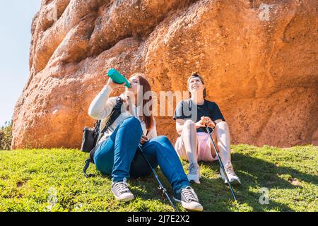 deux femmes randonneurs, se reposant sur l'herbe. jeunes femmes en vacances. femme buvant de l'eau d'une cantine. Banque D'Images