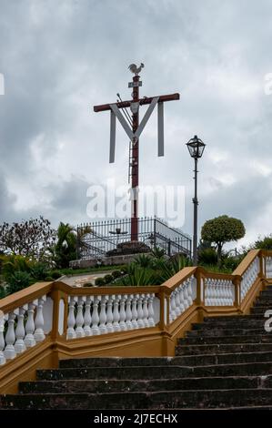 Une croix religieuse située sur le côté de l'escalier de l'église Nossa Senhora das Merces dans le centre historique et sous le ciel couvert. Banque D'Images