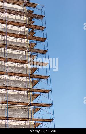 Échafaudage, échafaudage mobile en métal, fond bleu ciel. Un bâtiment moderne est en construction, un échafaudage en métal. Banque D'Images