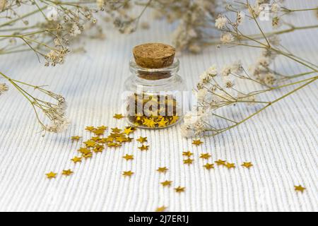 Superbes paillettes dorées brillantes éparpillées sur fond blanc tricoté texturé, vue rapprochée du dessus Banque D'Images