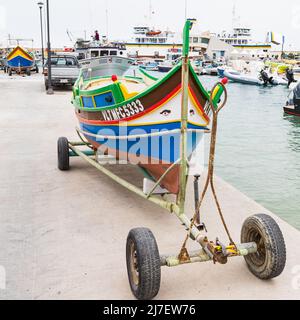 Un petit bateau Luzzu sur une remorque dans le port de Mgarr, Gozo qui attend d'être utilisé pour la pêche en avril 2022. Banque D'Images