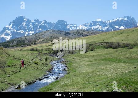 Randonneur dans la rivière Escarra avec des montagnes enneigées en arrière-plan, les Pyrénées Huesca. Banque D'Images