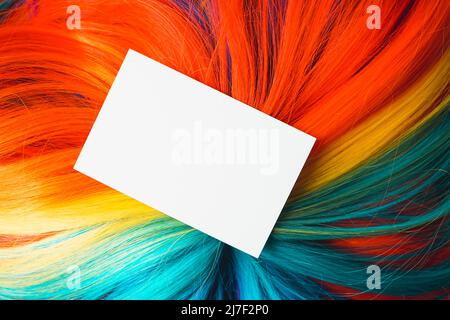 Maquette d'une carte blanche de très près sur une perruque arc-en-ciel colorée et multicolore avec beaucoup de texture de cheveux Banque D'Images