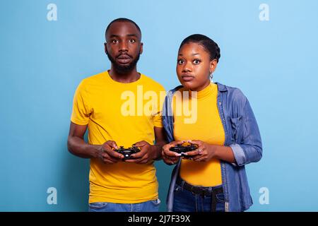 Petit ami et petite amie jouant à des jeux vidéo avec la manette sur la console. Couple moderne tenant le joystick pour jouer en ligne ensemble, en utilisant des accessoires à Amuse-toi bien. Activités de loisirs Banque D'Images