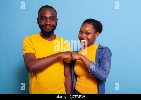 Portrait d'un couple souriant qui secoue les poings ensemble sur la caméra, célébrant le travail d'équipe réussi avec un geste d'accord. Petite amie et petit ami étant des partenaires et ayant des réalisations. Banque D'Images