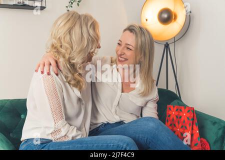 Une mère mûre heureuse et une petite fille adulte partagent un moment intime, une maman âgée souriante et une jeune fille millénaire embrassent. Photo de haute qualité Banque D'Images