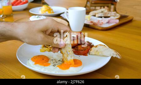 Trempez le pain dans le jaune d'œuf frit dans le restaurant ou le café, le petit-déjeuner ou le déjeuner Banque D'Images
