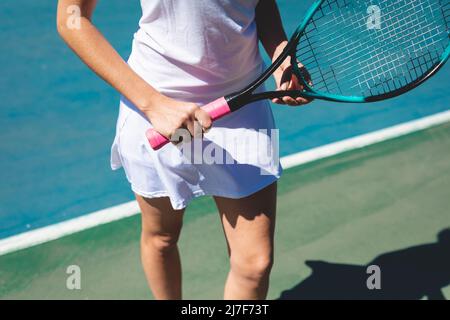 Section médiane de la jeune femme caucasienne tenant une raquette de tennis sur le court par beau temps Banque D'Images