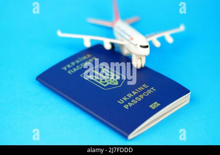 Passeport ukrainien sur fond bleu et un avion de jouet flou, foyer sélectif Banque D'Images