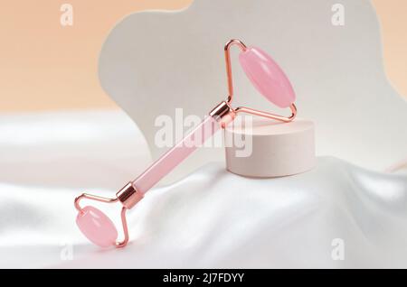 Rouleau en quartz pour un massage du visage sur un podium beige. Traitements anti-âge. Soins du visage Banque D'Images