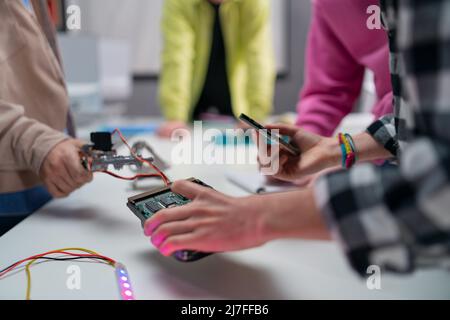 Des enfants avec un enseignant travaillant ensemble sur un projet avec des jouets électriques et des robots dans une salle de classe robotique, gros plan Banque D'Images